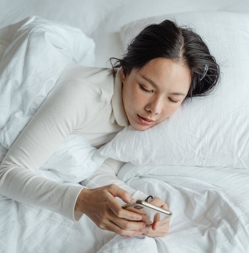 woman with iphone in bed